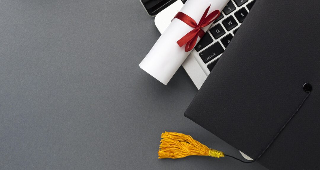 top view laptop with diploma academic cap